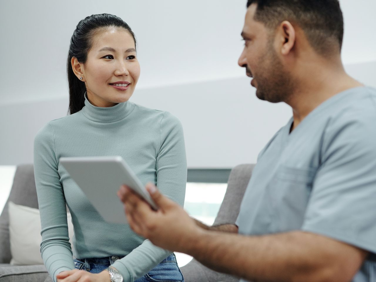 A care provider showing information on a tablet to a smiling patient.